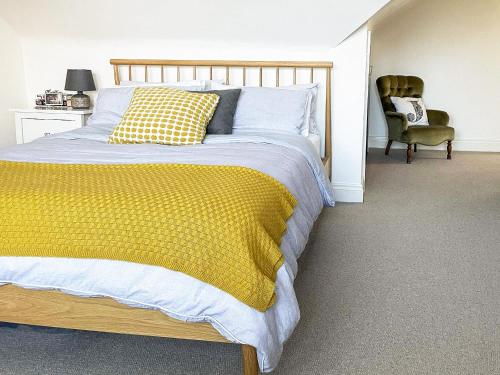 a bedroom with a bed with a yellow blanket and a chair at Cosy Apartment in Winchester