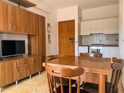 una cucina con tavolo in legno, sedie e TV di Brain Apartment Scalea - Parco Edil Blu a Scalea