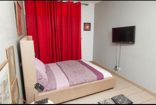 a bedroom with a bed and a red curtain at DUPLEXE HAUT STANDING centre ville Quartier Fouda in Yaoundé