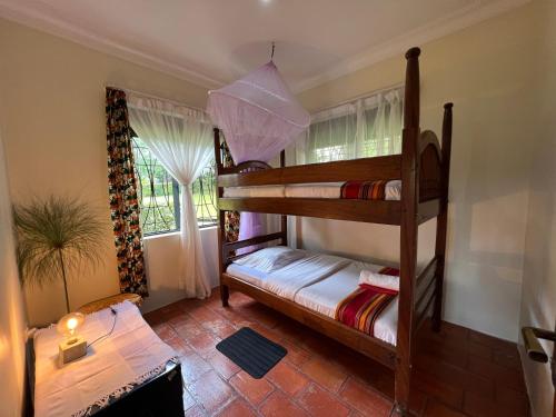Farm Cottage في Mukono: سريرين بطابقين في غرفة مع نافذة