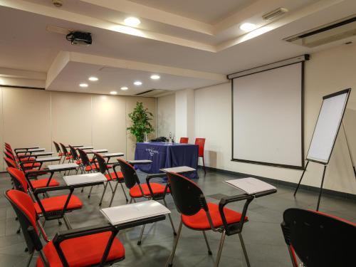 a classroom with desks and chairs and a screen at La Meridiana Bleisure Hotel in Perugia
