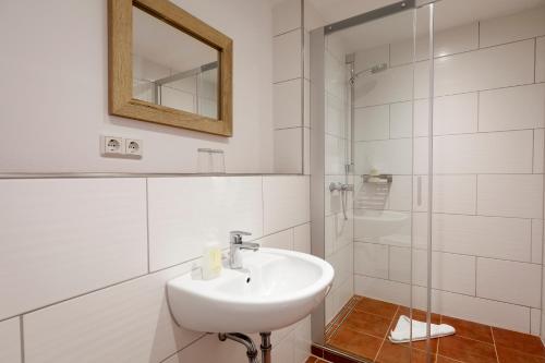a white bathroom with a sink and a mirror at Hotel Helgolandia in Helgoland