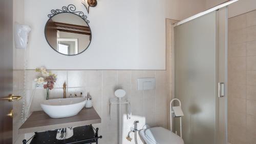 a bathroom with a sink and a toilet and a mirror at CASA LA FENICE 8&2, Emma Villas in Pomarance