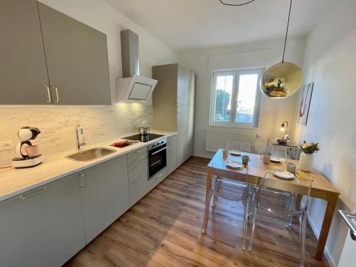 a kitchen with white cabinets and a table with chairs at Ferienwohnung Freude am Kurpark in Bad Neuenahr-Ahrweiler