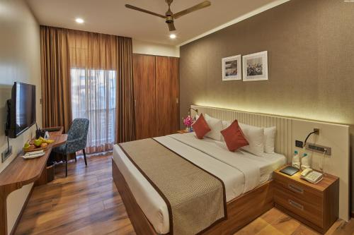 a hotel room with a bed and a desk and a television at Regenta Inn Grand-ORR, Mahadevapura in Bengaluru
