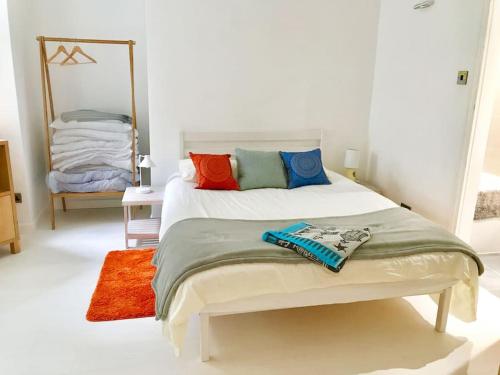 Spacious two bedroom, two bathroom Beach Nest with garden في سانت ليوناردز: غرفة نوم مع سرير مع وسائد ملونة