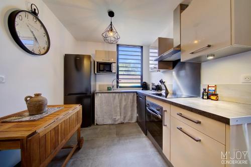 a kitchen with a large clock on the wall at Ylangae DODO avec Jacuzzi à 150m du lagon in Saint-Leu