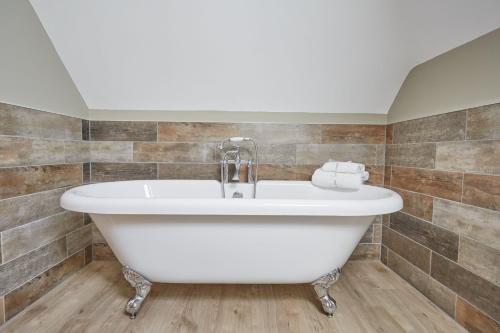 a white bath tub in a bathroom with tiles at Red Oak Barn, Ashlin Farm Barns in Lincoln