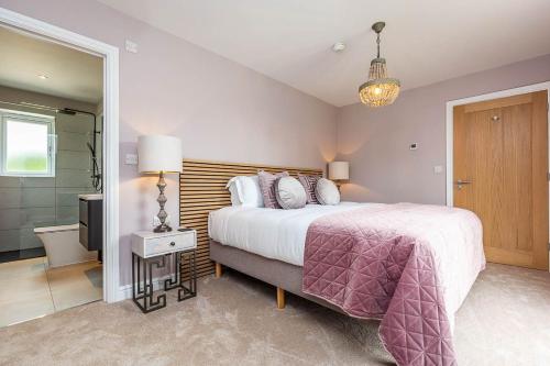 a bedroom with a large bed and a bathroom at The Elms, Ashlin Farm Barns in Lincoln