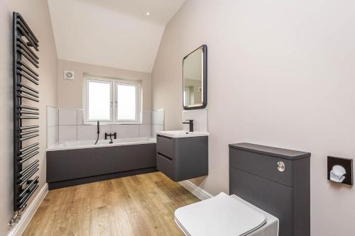 a bathroom with a tub and a sink and a toilet at The Elms, Ashlin Farm Barns in Lincoln