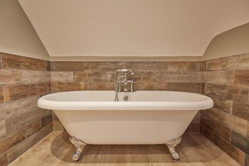 a white bath tub in a bathroom with brown tiles at Holly Tree Barn, Ashlin Farm Barns in Lincoln