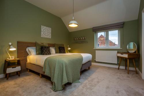 a green bedroom with a bed and a window at The Hazels, Ashlin Farm Barns in Lincoln