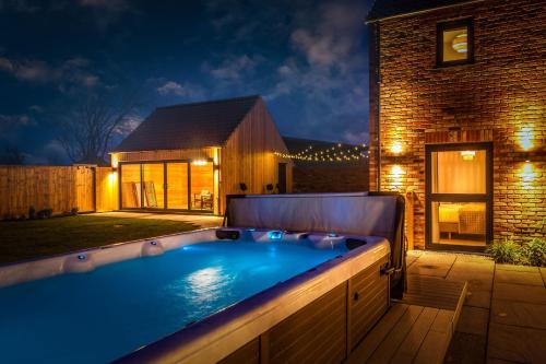 una piscina en el patio trasero de una casa por la noche en The Birches, Ashlin Farm Barns en Lincoln