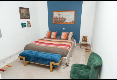 a bedroom with a bed and a green chair at DUPLEXE HAUT STANDING centre ville Quartier Fouda in Yaoundé