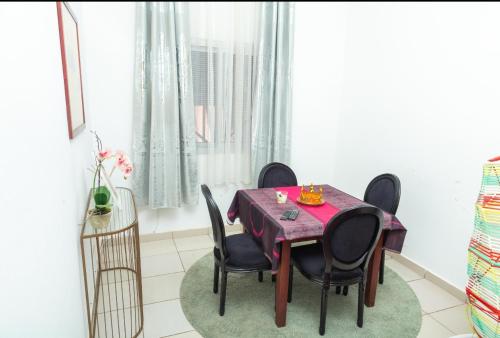 a dining room with a purple table and black chairs at DUPLEXE HAUT STANDING centre ville Quartier Fouda in Yaoundé
