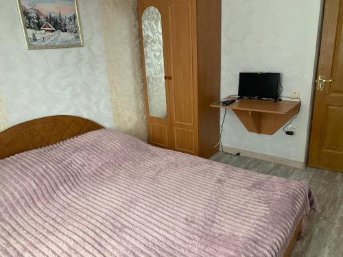a bedroom with a bed and a desk and a television at Svitlyachok in Yaremche