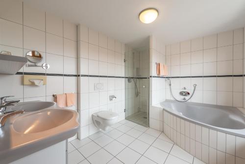 a bathroom with a tub and a toilet and a sink at Gasthaus Hotel Zum Mohren in Niederstotzingen