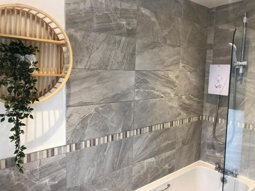 a bathroom with a bath tub and a mirror at Barber House, Hoyland in Hoyland Nether