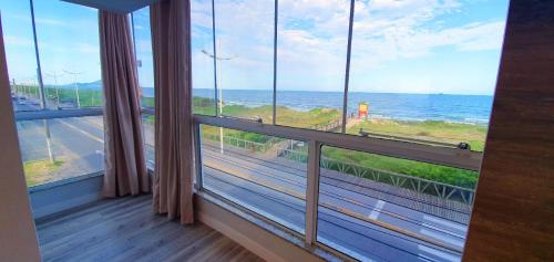 a room with a large window with a view of the ocean at Navega Beach Palace Hotel in Navegantes