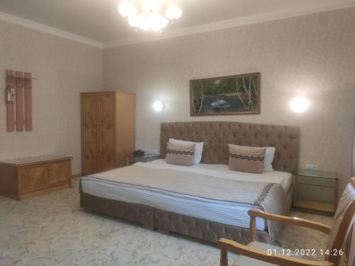 a bedroom with a large bed and a chair at Asia Hotel Fergana in Fergana