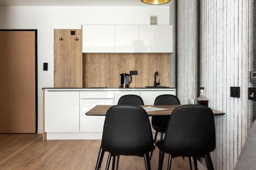 a kitchen with a wooden table and black chairs at InPoint Apartments G15 near Old Town & Kazimierz District & Optional Paid Parking in Kraków