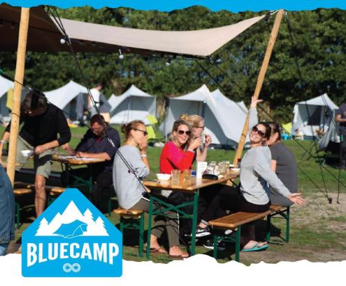 um grupo de pessoas sentadas numa mesa numa tenda em BlueCAMP Oerol24- Tent&Breakfast em West-Terschelling