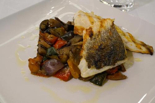 a white plate of food with a sandwich and vegetables at La Meridiana Bleisure Hotel in Perugia