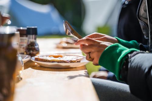 een persoon aan een tafel met een bord eten bij BlueCAMP Oerol24- Tent&Breakfast in West-Terschelling