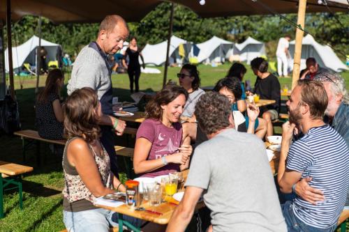een groep mensen die aan tafel zitten op een feestje bij BlueCAMP Oerol24- Tent&Breakfast in West-Terschelling