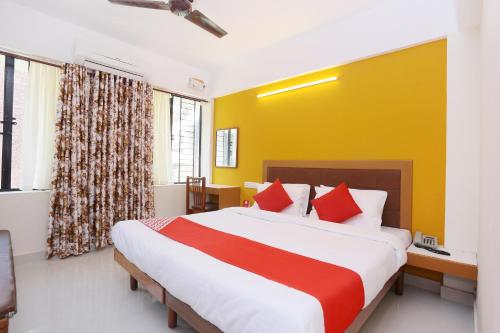 a bedroom with a large bed with a yellow wall at Hotel Ganesh in Trivandrum