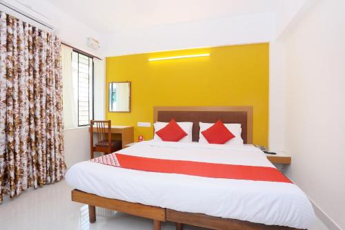 a bedroom with a large bed and a yellow wall at Hotel Ganesh in Trivandrum