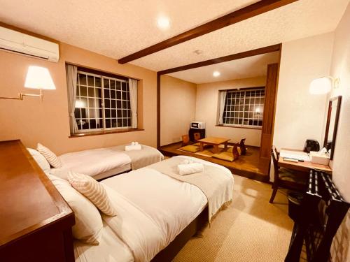 a hotel room with two beds and a desk at Hostel SAMURISE NORTH in Fujikawaguchiko