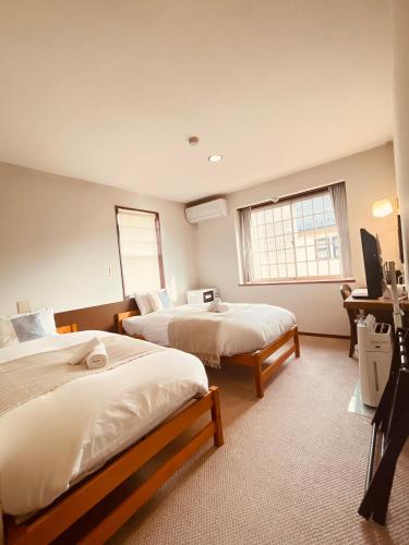 a hotel room with two beds and a television at Hostel SAMURISE NORTH in Fujikawaguchiko
