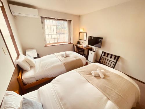 a hotel room with two beds and a television at Hostel SAMURISE NORTH in Fujikawaguchiko