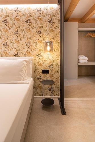 a bedroom with a bed and a stool next to a wall at Relais Limonaia - Suites & Garden SPA in Torri del Benaco