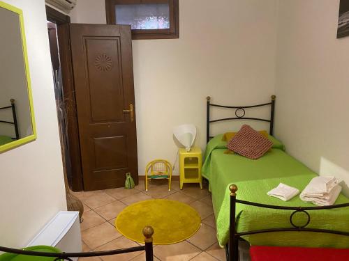 a small bedroom with a green bed and a door at Place San Pantaléo : jolie maison sarde authentique in San Pantaleo
