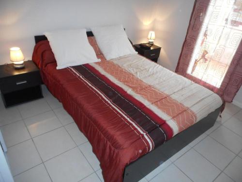 - un lit avec une couverture rouge et 2 tables de chevet dans l'établissement Appartement Hendaye, 2 pièces, 4 personnes - FR-1-2-291, à Hendaye