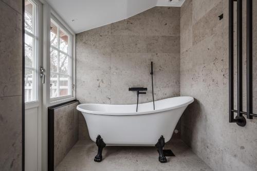 a white bath tub in a bathroom with a window at Trädgårdsmästarbostaden / The Gardeners Villa in Gävle