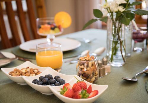 a table topped with bowls of fruit and a glass of orange juice at Mirihof Retreat and Olive Estate in Montagu
