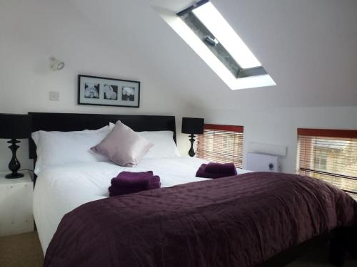 a bedroom with a large white bed with purple sheets at The Stables, Lower Mill Estate in Somerford Keynes