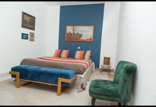 a bedroom with a bed and a green chair at DUPLEXE HAUT STANDING centre ville Quartier Fouda in Yaoundé