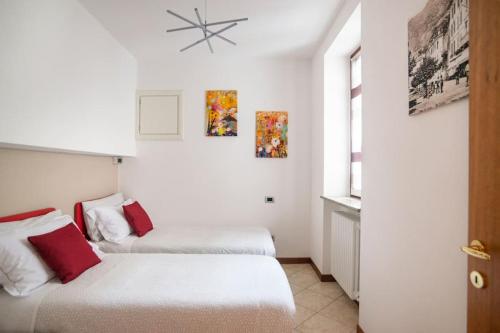 2 letti in una camera con pareti bianche e cuscini rossi di Villa Vista Lago di Como by villavistalago a Bellano