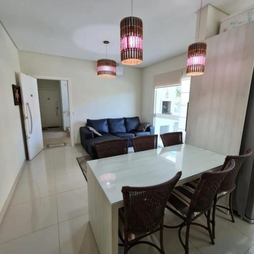 eine Küche und ein Wohnzimmer mit einem Tisch und Stühlen in der Unterkunft novo e aconchegante apartamento a 90 metros da praia de bombinhas in Bombinhas
