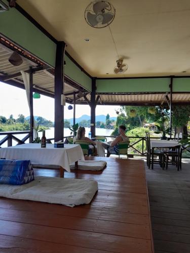 a restaurant with tables and people sitting on a deck at Rivergarden Guesthouse and restaurant in Don Det