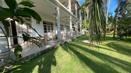 eine Veranda eines Hauses mit grünem Gras und Palmen in der Unterkunft Wilson's Place in Hiriketiya