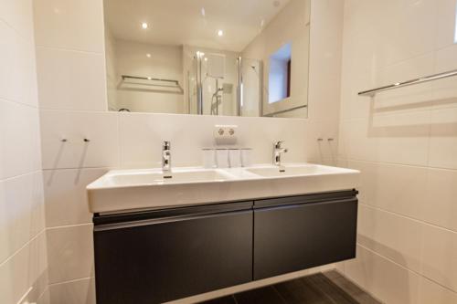 a white bathroom with a sink and a mirror at Chalet Hohe Tauern - Steinbock Lodges in Zell am See