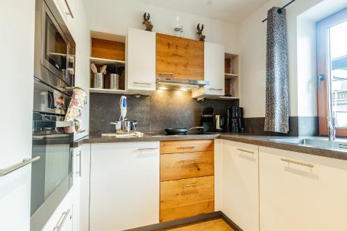 a white kitchen with wooden cabinets and a window at Chalet Hohe Tauern - Steinbock Lodges in Zell am See