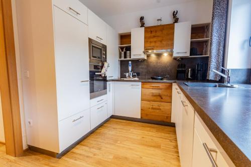 a kitchen with white cabinets and a wooden floor at Chalet Hohe Tauern - Steinbock Lodges in Zell am See