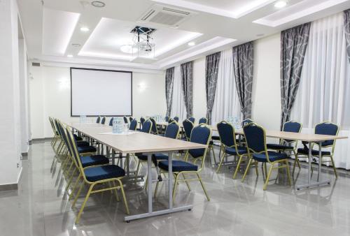 a conference room with tables and chairs and a projection screen at Hotel Polonia in Biała Podlaska