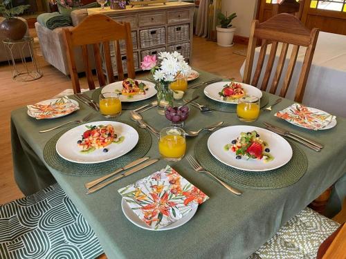 a table with plates of food and glasses of orange juice at Mirihof Retreat and Olive Estate in Montagu